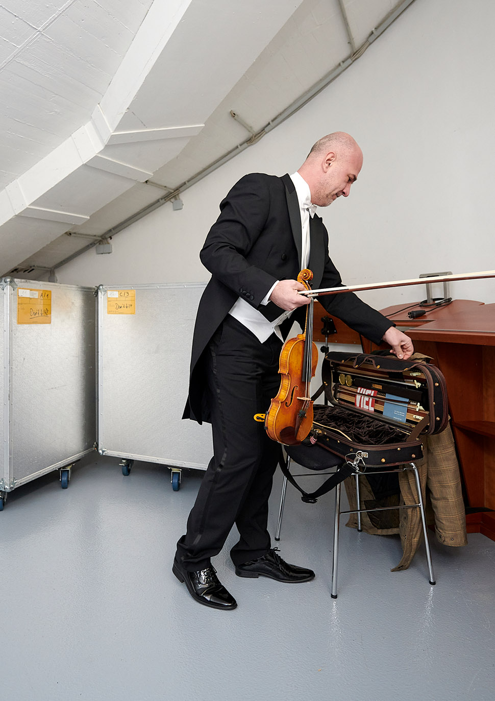 Konzertmeister bereitet sich in einem Abstellraum auf das Konzert vor.
